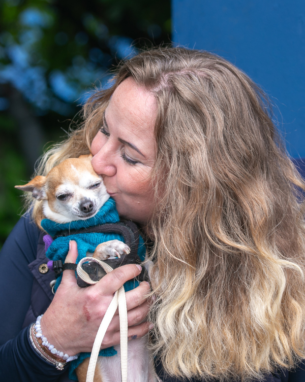 woman kissing a dog in her hands